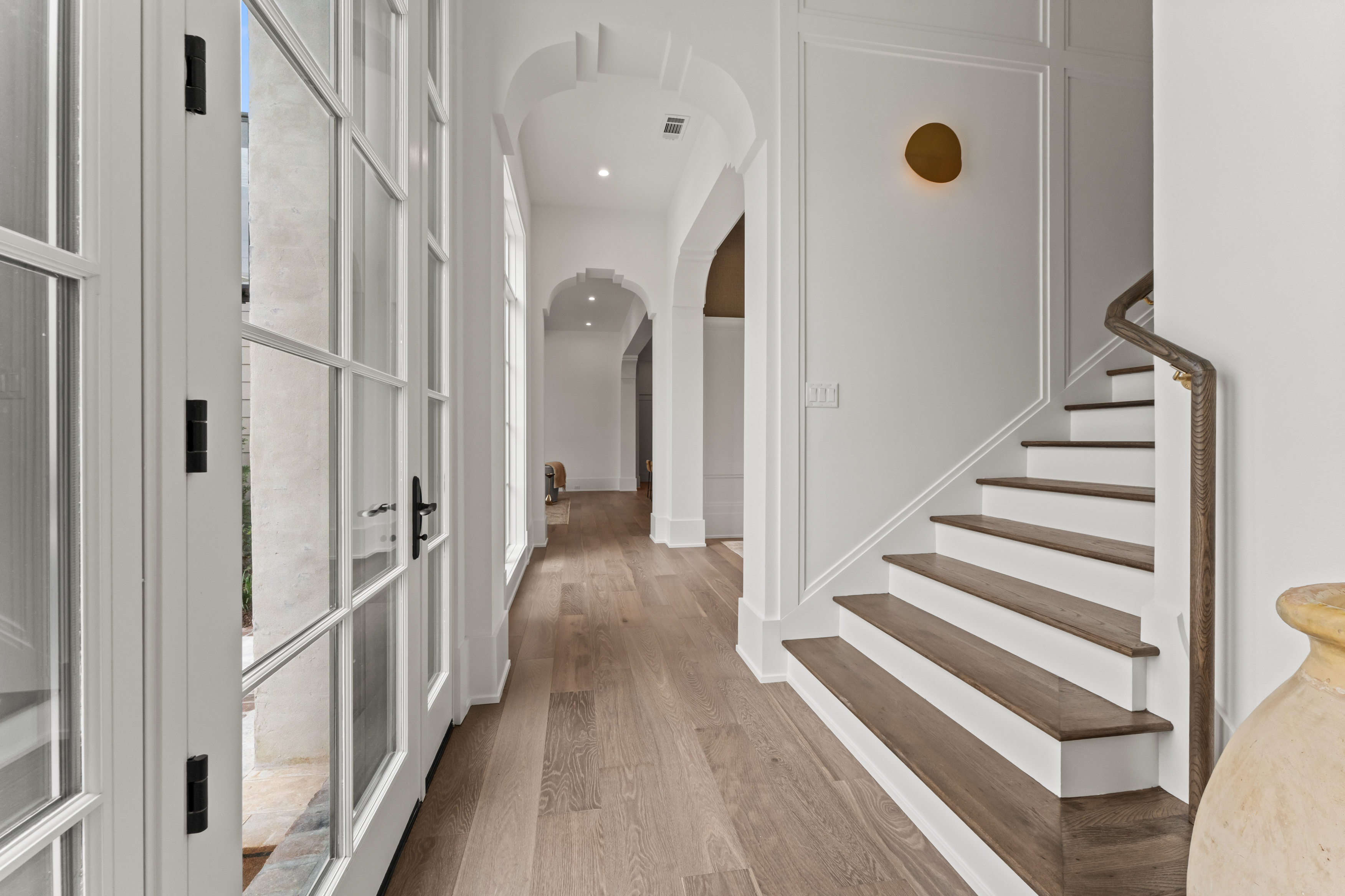 Arched openings, wood floors, and the stair define the entry hall.