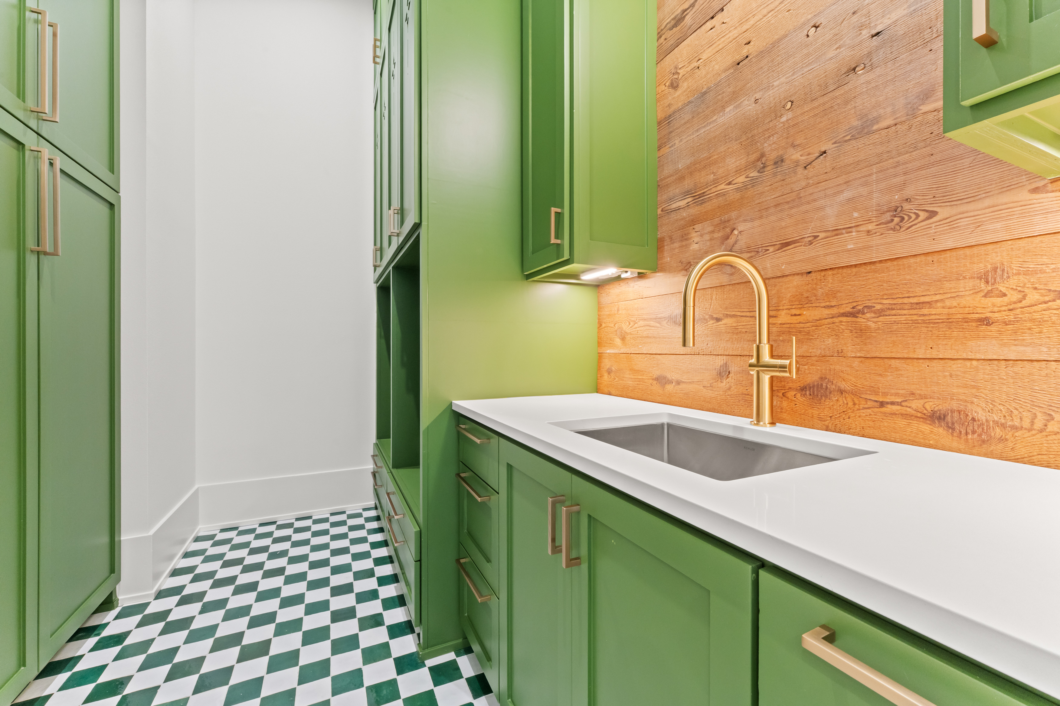 Green cabinetry and warm wood bring character to the laundry room.