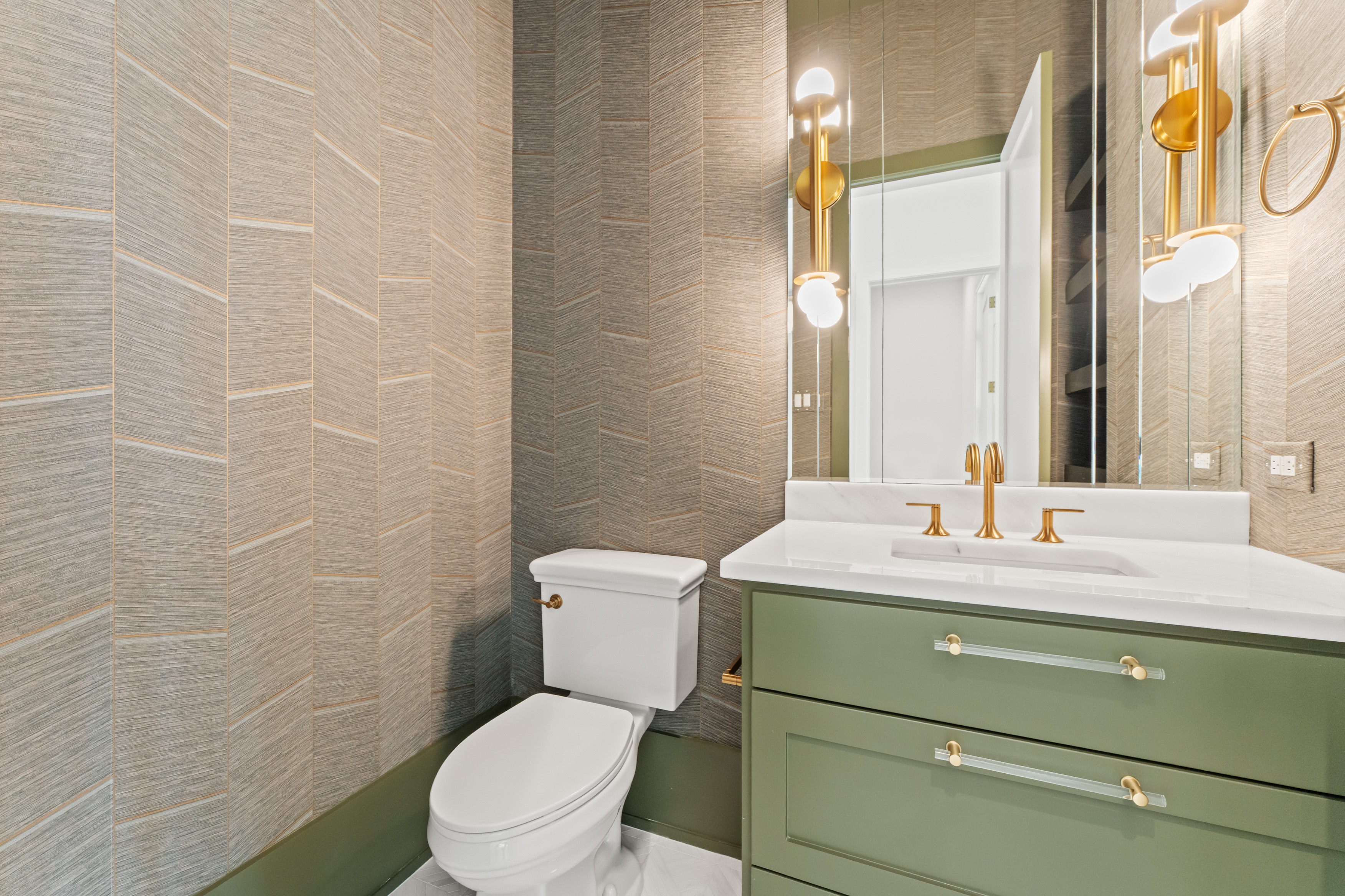 A compact powder room composed with textured tile and aged brass.