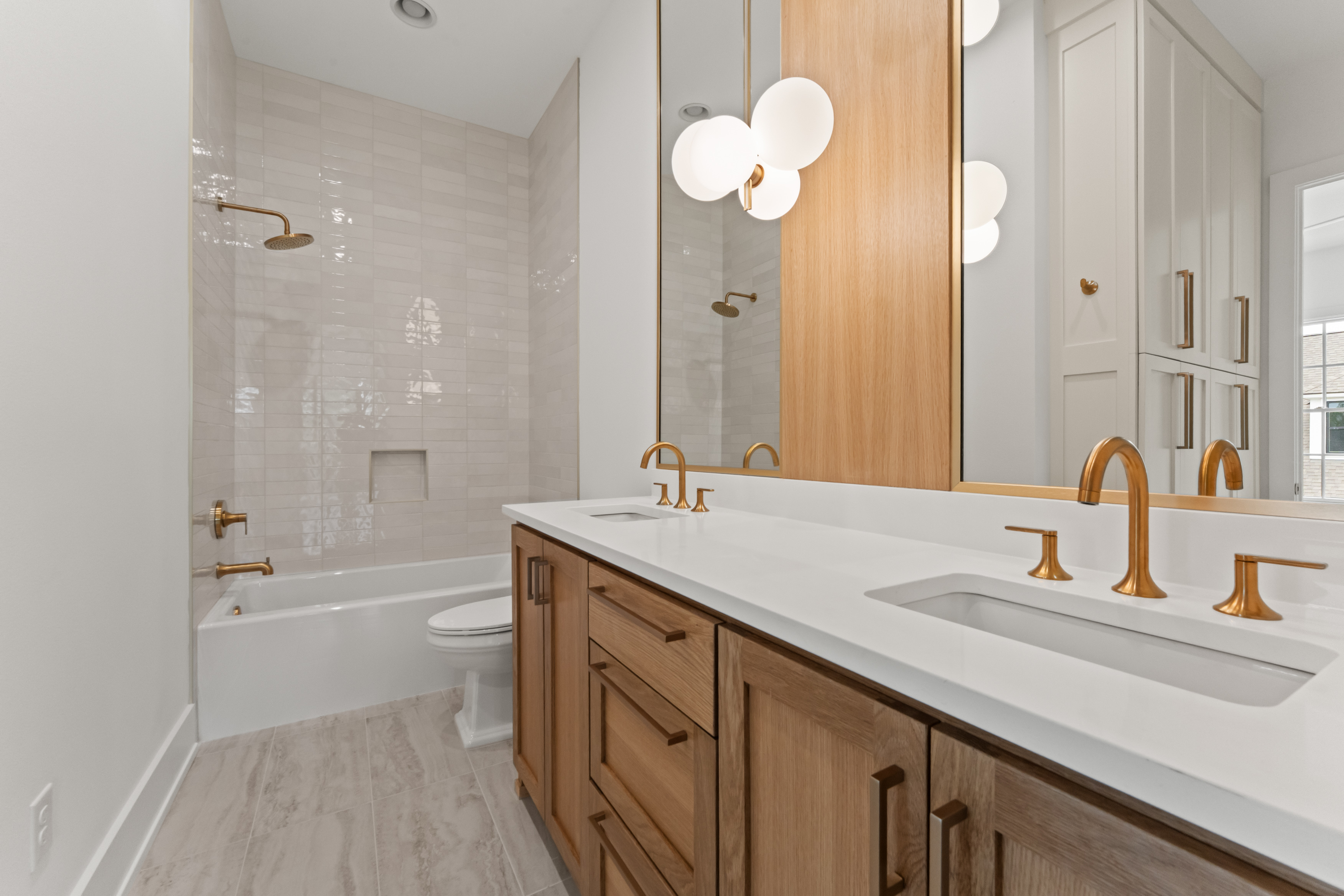 Natural wood cabinetry and a glass shower in a secondary bath.