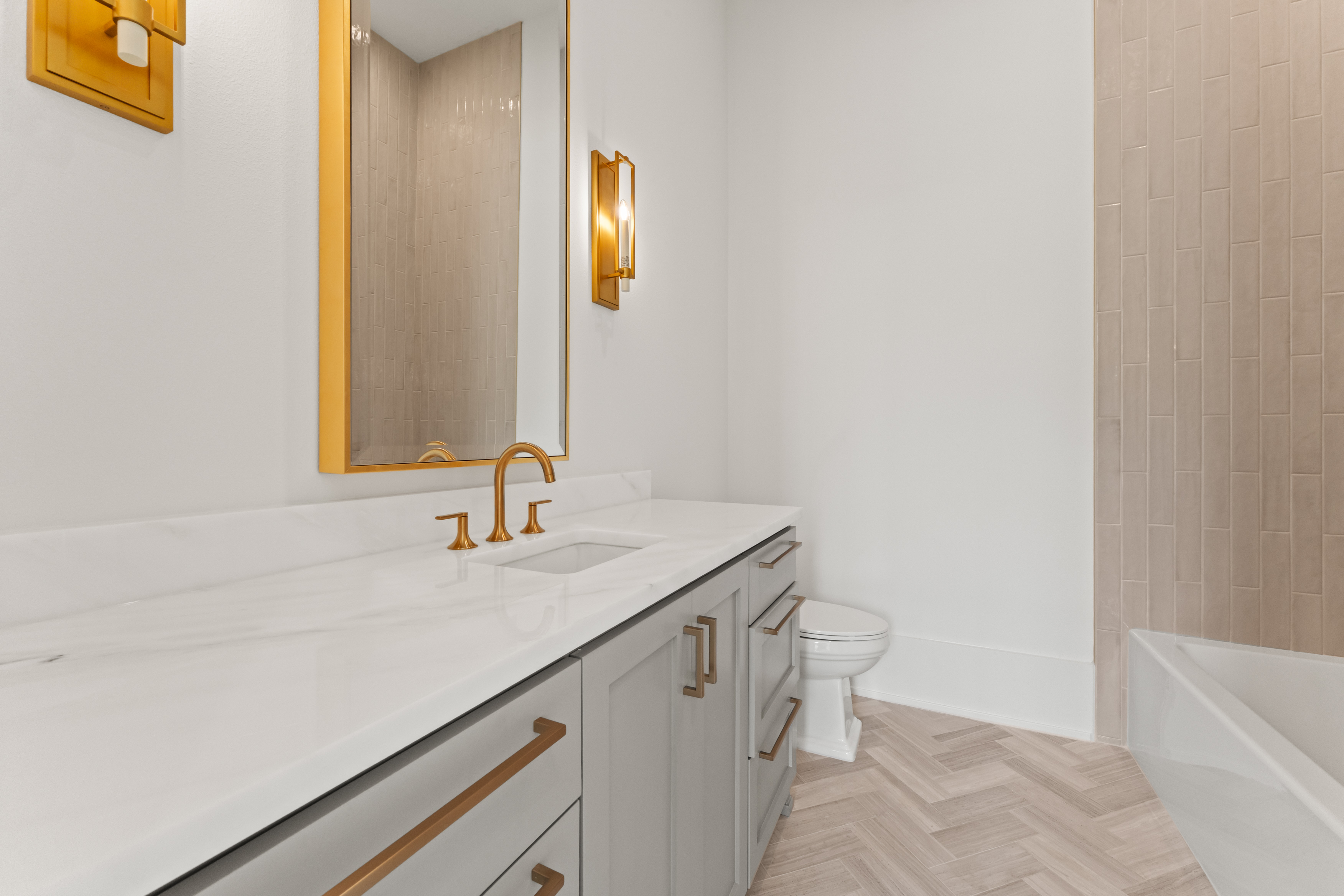 Quiet stone and brass detailing at a guest bath vanity.