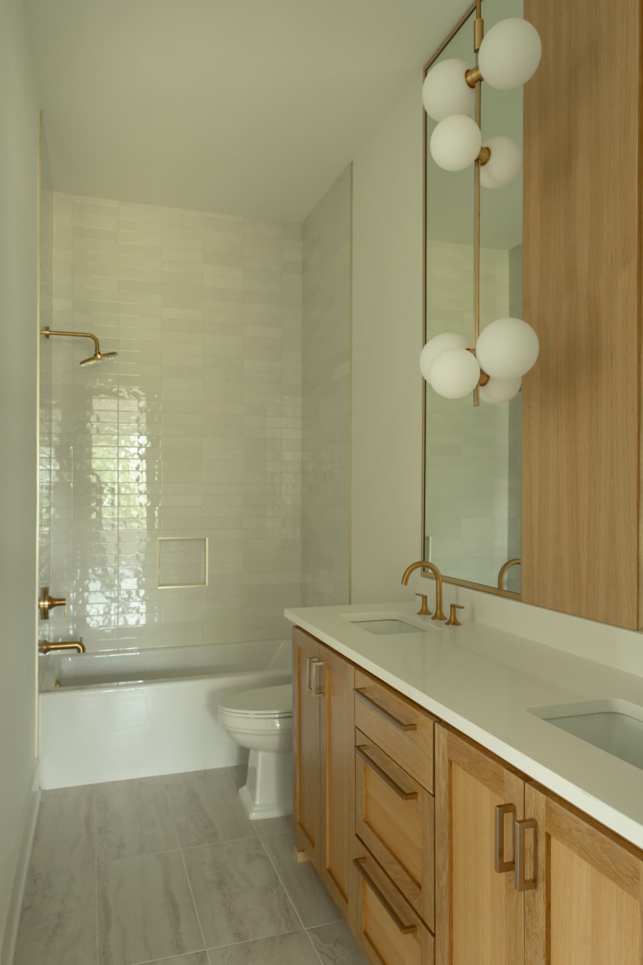 Renovated bathroom with white oak vanity, glazed tile, and brass fixtures