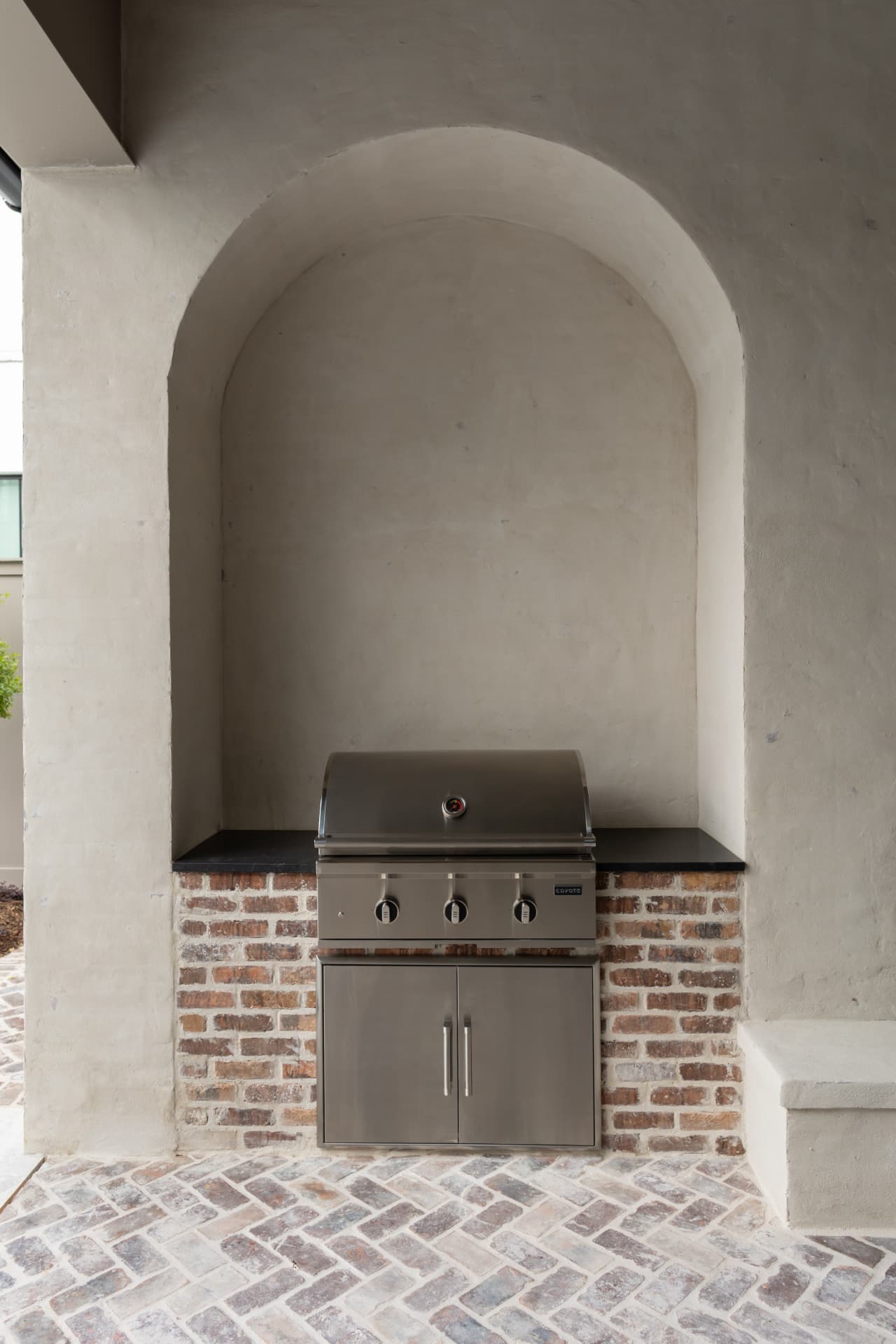 Stucco arch and reclaimed brick outdoor kitchen built by Burns Construction Group