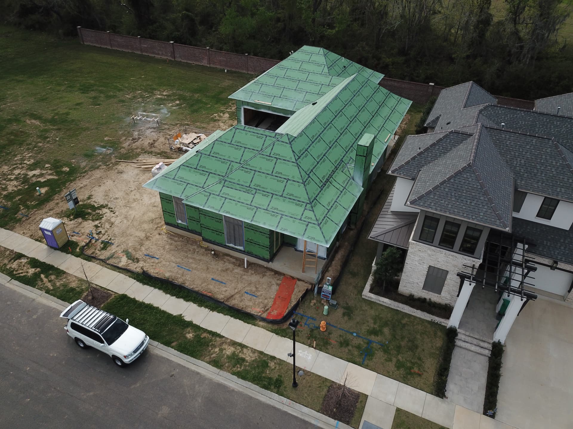 Aerial view of a custom home under construction on a Greater Baton Rouge homesite, framed and sealed for the roof